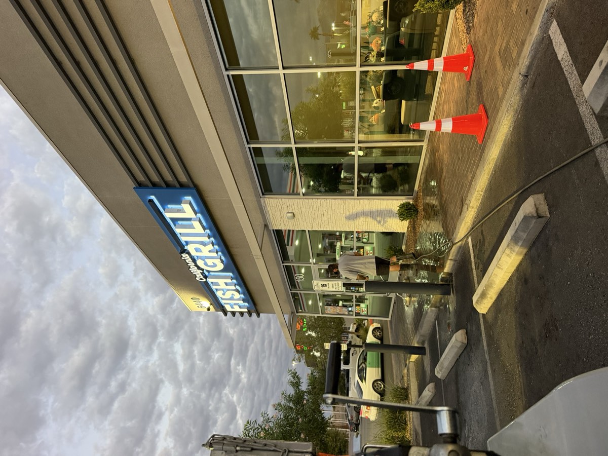 Poseidon crew power washing a storefront walkway